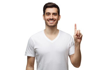 Fototapeta premium Young smiling man pointing up with his finger isolated on white gray background