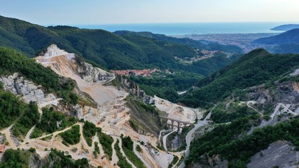 Fototapeta premium Aerial view of mountain of stone and marble quarries in the regional natural park of the Apuan Alps located in the Apennines in Tuscany, Massa Carrara Italy. Open pit mine