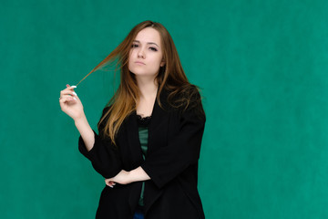 Concept portrait for a belt of a pretty girl, young woman with beautiful brown hair and in a black jacket and green T-shirt on a green background. In the studio in different poses showing emotions.