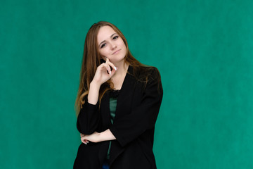 Concept portrait for a belt of a pretty girl, young woman with beautiful brown hair and in a black jacket and green T-shirt on a green background. In the studio in different poses showing emotions.