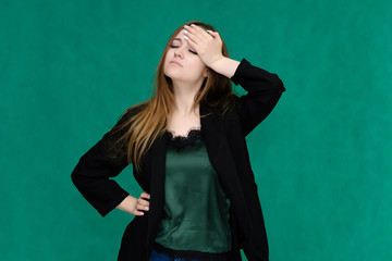 Concept portrait for a belt of a pretty girl, young woman with beautiful brown hair and in a black jacket and green T-shirt on a green background. In the studio in different poses showing emotions.