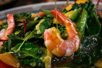  shrimp watered with sauce on the background of spinach and arugula salad