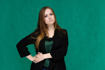 Concept portrait for a belt of a pretty girl, young woman with beautiful brown hair and in a black jacket and green T-shirt on a green background. In the studio in different poses showing emotions.