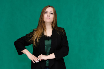 Concept portrait for a belt of a pretty girl, young woman with beautiful brown hair and in a black jacket and green T-shirt on a green background. In the studio in different poses showing emotions.