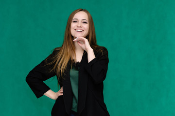 Concept portrait for a belt of a pretty girl, young woman with beautiful brown hair and in a black jacket and green T-shirt on a green background. In the studio in different poses showing emotions.