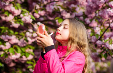 Girl in cherry flower. Kid with lipstick makeup. Small girl child in spring flower bloom. Smell of tender bloom. Sakura flower concept. Gorgeous flower and female beauty. Natural cosmetics for skin