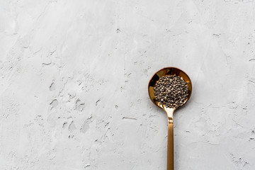 Chia seeds in spoon lying on gray concrete background. Vegetarian food. Diet for weight. Healthy eating concept. Flat lay, mockup, overhead, top view with copy space