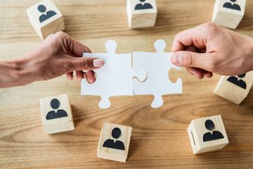 top view of african american woman and man holding jigsaw puzzle pieces near wooden cubes