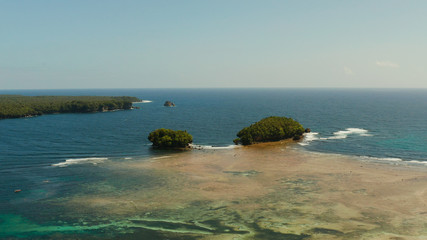 Aerial view of tropical islands in the ocean with waves crashing on the shore, top view. Siargao, Philippines. Summer and travel vacation concept.