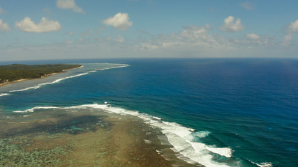 Tropical island coastline with beach and ocean with surf and coral reef top view. Summer and travel vacation concept