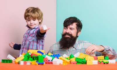 Father son play game. Father and son create colorful constructions with bricks. Child care development and upbringing. Bearded father and boy play together. Dad and kid build of plastic blocks