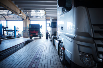 Truck repair shop interior with workers checking trucks.