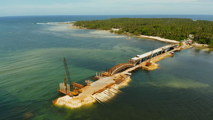Heavy construction equipment and workers in the construction of a bridge across the strait. Siargao, Philippines