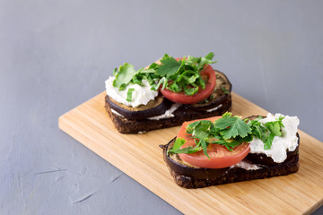 Bruschetta with Grilled Eggplant Tomatoes Cottage Cheese and Fresh Aromatic Herbs on a Wooden Tray Delicious Mediterranean Appetizer Dish Gray Background