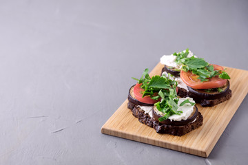 Bruschetta with Grilled Eggplant Tomatoes Cottage Cheese and Fresh Aromatic Herbs on a Wooden Tray Delicious Mediterranean Appetizer Dish Gray Background