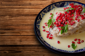 Chile en nogada en plato de talavera sobre una mesa de madera