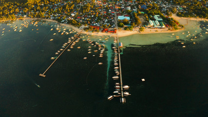 City General Luna on the coast of Siargao with a pier, a port and tourist boats at sunrise, aerial view. Summer and travel vacation concept.
