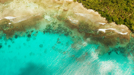 Waves rashing on beach and coral reef copy space for text, aerial view. Sea water surface in lagoon with coral reef. Summer and travel vacation concept.