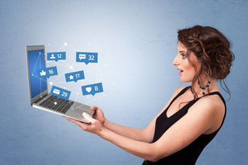 Woman holding laptop with different types of social media symbols and icons