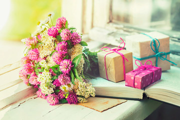 Bouquet of clover, a gift and a book on the window, selective focus.