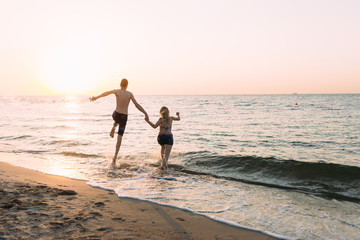 Fototapeta na wymiar in love and happy couple fun runs and jumps into the ocean. Enjoy life,