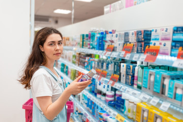 Young lovely woman chooses mouthwash. Purchase and sale of goods in the store