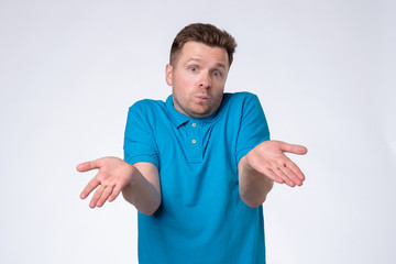 Confused handsome guy showing I have no idea gesture, shrugging shoulders and raising hands