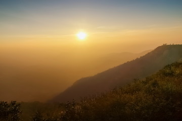 Mountain view morning of top hill around with soft fog and yellow sun light in the sky background, sunrise at top of Phu Ruea National Park, Phu Ruea District, Loei Province, Thailand.