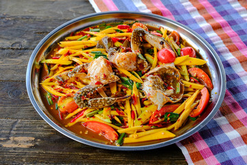 Mango papaya salad with blue crab Placed in a beautifully placed tray on a Thai style wooden table