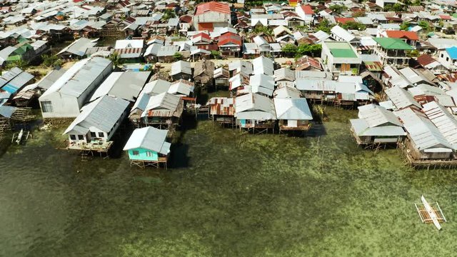 Fishing village with boats and slums with wooden houses, aerial drone. Dapa, Siargao, Philippines.