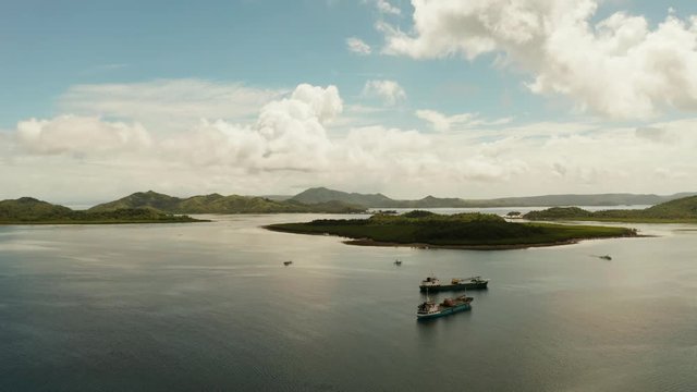 Cargo ships moored in a bay among tropical islands. Dapa Ferry Terminal. Siargao, Philippines.