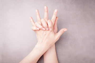Beautiful female hands on a gray background. Manicure with nude nail polish. Manicure care concept. Copy space
