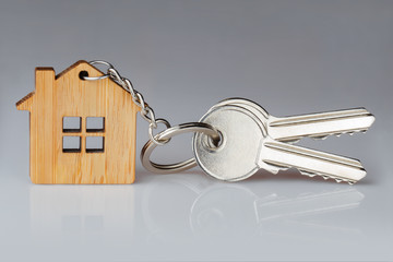 House keys with a house shaped keychain on gray background