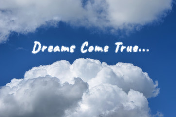 Cloudy inscription Dreams Come True... in blue sky with snowy-white clouds