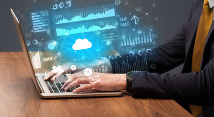 Businessman hand typing on laptop with reports and graphs concept around
