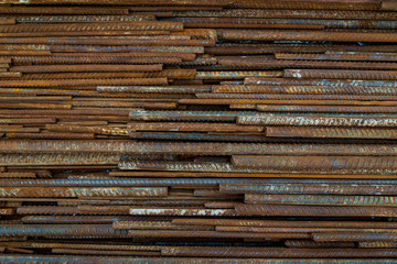 Top view stack of straight old rusty high yield stress deformed reinforcement steel or iron bars. Background horizontal random pattern of deformed iron bars. 