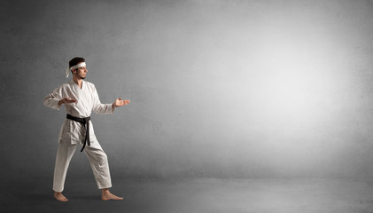 Small karate man fighting in an empty grey copy space