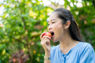 Portrait of beautiful middle aged asian women holding apple in park