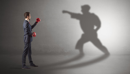 Obraz premium Businessman fighting with his strong karate man shadow
