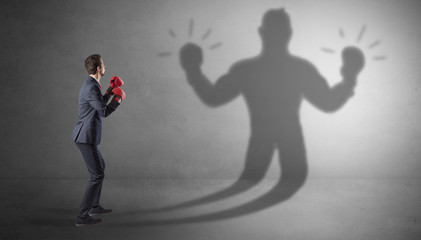 Businessman trying to fight with his unarmed shadow