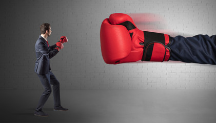 Tiny businessman fighting with boxing gloves