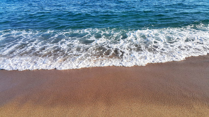Sea wave with white foam on the sandy beach