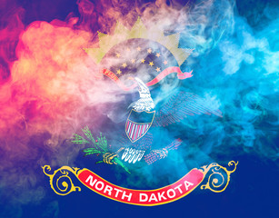 The national flag of the US state North Dakota in against a gray smoke on the day of independence in different colors of blue red and yellow. Political and religious disputes, customs and delivery.