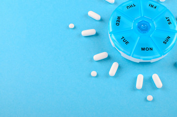 different medicines for one week and a pills box on blue background with copy space