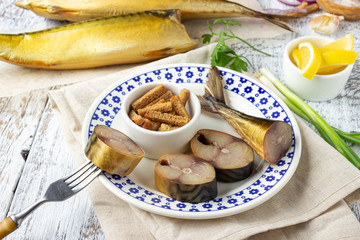 Beer snack - smoked fish mackerel and crispy croutons on white wooden table.