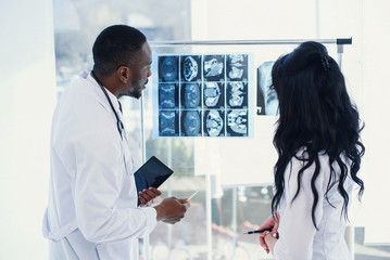Two doctors look at an x-ray and discuss the problem. Medical technicians pointing at MRI x-ray of...