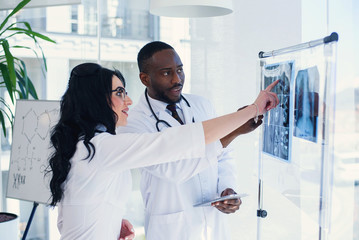 Two doctors look at an x-ray and discuss the problem. Medical technicians pointing at MRI x-ray of...