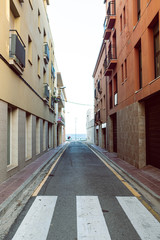 Narrow urban street with zebra crossing and big buildings