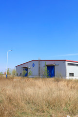 Weeds and warehouse under blue sky