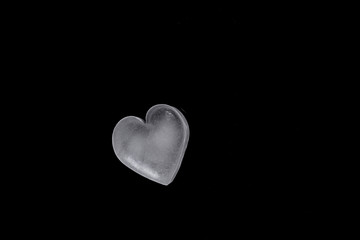 icy cold heart shaped ice cube on a black background